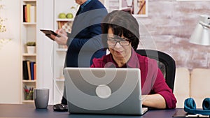 Retired woman working on laptop in living room