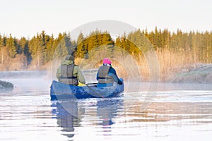 retirees rowing a canoe in early spring in the early morning. seniors lifestyle. Morning landscape, fog by the morning