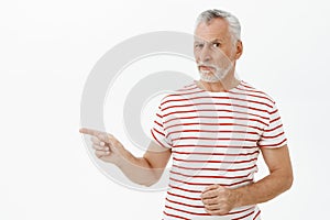 Retirement, age and people concept. Portrait of hesitant doubtful handsome old male with white beard in striped t-shirt