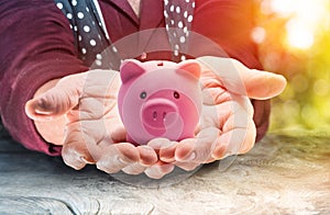 Retirement Concept - Elderly Lady Holding A Piggy Bank At Sunset