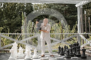 Retirement. Funny smiling playing chess on big chessboard in the park. Chess game for old man. Older grandfather