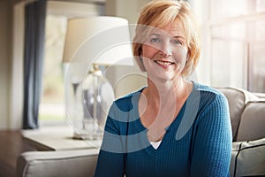 Retirement gave me a lot of reasons to smile. Portrait of a happy mature woman relaxing on the sofa at home.