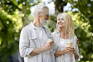 Retirement Leisure. Smiling Senior Spouses Walking Outdoors And Drinking Takeaway Coffee