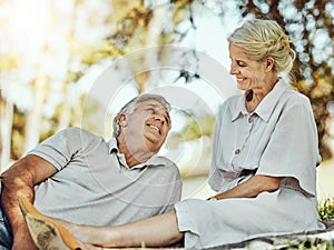 Retirement, love and picnic with a mature couple outdoor in nature to relax on a green field of grass together. Happy