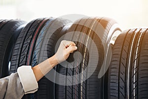 Retirement man touching and choosing for buying a tire in a supermarket mall. Measuring rubber car wheel