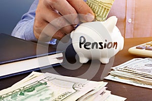 Retirement plan. Man is putting dollar banknote in a piggy bank with sign pension.