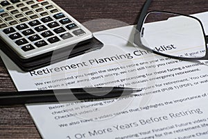 Retirement planning checklist with calculator, glasses and pencil focuus on words retirement planning checklist.