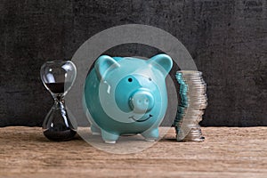 Retirement saving money piggy bank as long term investment concept with stack of coins and sandglass or hourglass on wood table