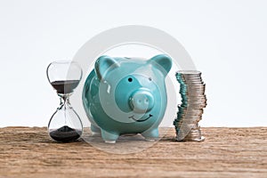 Retirement saving money piggy bank as long term investment concept with stack of coins and sandglass or hourglass on wood table