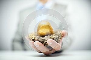 Retirement savings golden nest egg in businessman hand photo