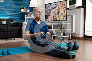 Retirement senior man sitting on yoga mat stretching legs muscles