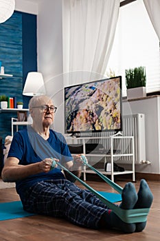 Retirement senior man sitting on yoga mat stretching legs muscles