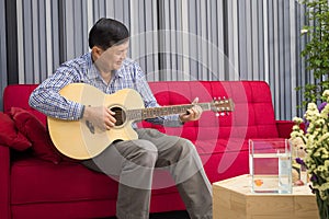 Retirement seniors sitting on a sofa playing guitar happily in the living room