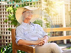 Retirement, a time for rest and reflection. Shot of a thoughtful senior woman relaxing on a bench in the garden.