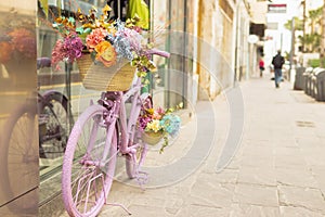 retor bicycle of pink color stands near the shop window decorated with flowers