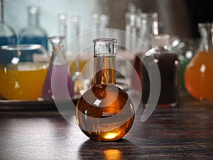 Retort with amber liquid. Laboratory glassware with colorful liquids on the table