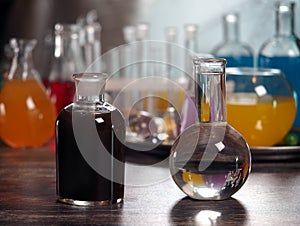 Retort with clear water and a dark bottle. Laboratory glassware with colorful liquids on the table