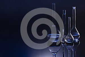 Retort flask on glass table with blue liquid on table against blue background. Laboratory analysis