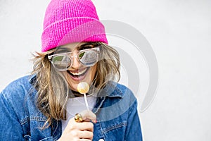 Retrato de mujer sonriendo alegre con gorro y gafas disfrutando del chupa chups photo