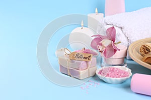 Retreat concept. Burning candles, orchid flower and different spa products on light blue background. Space for text
