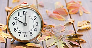 Retro alarm clock with autumn leaves, daylight savings time concept, web banner