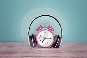 Retro alarm clock with headphone isolated on table, Vintage style pastel color background