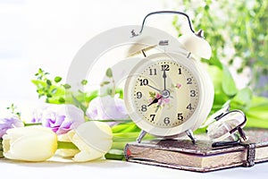 Retro alarm clock, notebook and spring flowers