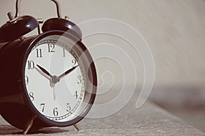 Retro alarm clock on table at outdoor patio with sun light blurred  background