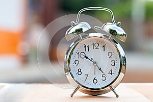 Retro alarm clock on wood table with bokeh background