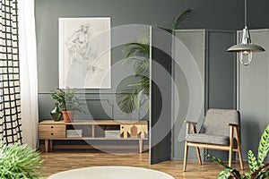 Retro armchair against a gray screen next to a drawing hanging o
