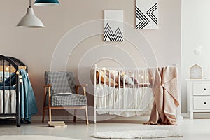 Retro armchair between two wooden cribs in cute twins nursery