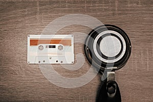 Retro audio tape and headphones on brown wooden background.