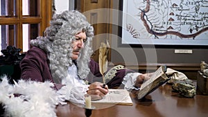 Retro baroque man with white wig holding a quill pen, sitting at antique table and thinking about paper documents