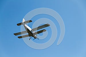 A retro biplane flying at high speed high in the air against a blue, cloudless sky