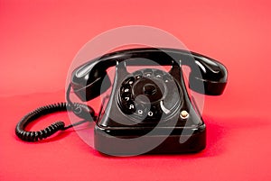 Retro black phone isolated on a red background