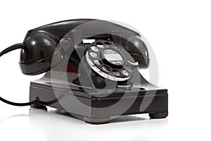 A retro black rotary phone on a white background