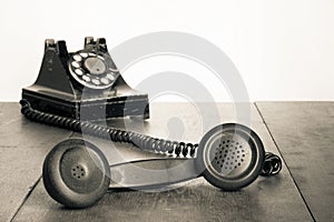 Retro black telephone on old oak wooden table. Vintage style sepia photo