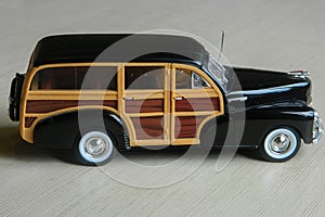 Retro black toy car on gray striped surface. Model of classic vintage sport car with shadows and partly soft focus. Side view of