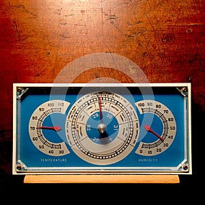 Retro blue barometer with wood background.