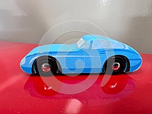 Retro blue sport car toy on a red shelf