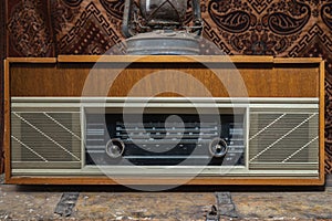 Retro broadcast radio receiver with blue eye light on wooden table circa 1950 front retro wall background. Listen music