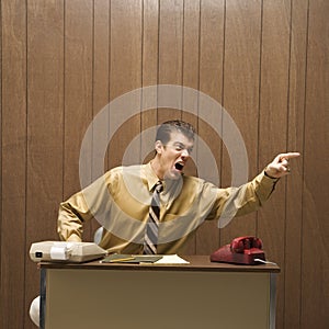 Retro business scene of angry man at desk.