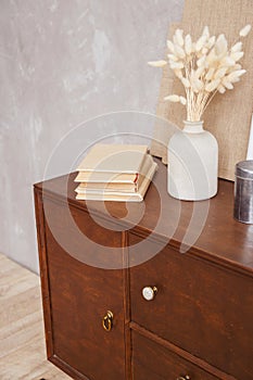 Retro cabinet with books and vase in home office interior on desk. Real photo