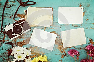 Retro camera and empty old instant paper photo album on wood table with flowers border design