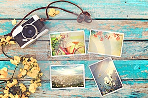 Retro camera and instant paper photo album on wood table with flowers border design