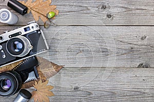 retro camera, lenses and negative film on wooden table background with yellow leaves