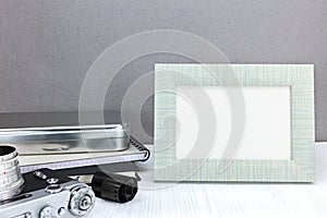 Retro camera, negative film roll and empty photo frame on grey b