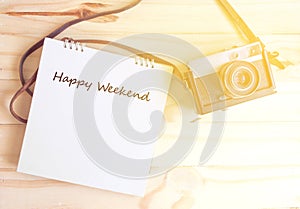 Retro camera and notepad writing happy weenkend with sunlight