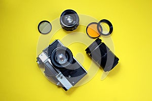 Retro camera. Old film camera and lenses lies on a yellow background
