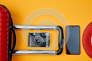 Retro camera and smartphone beside suitcase on yellow background. Travel blogging or woman blogger or summer vacation conception